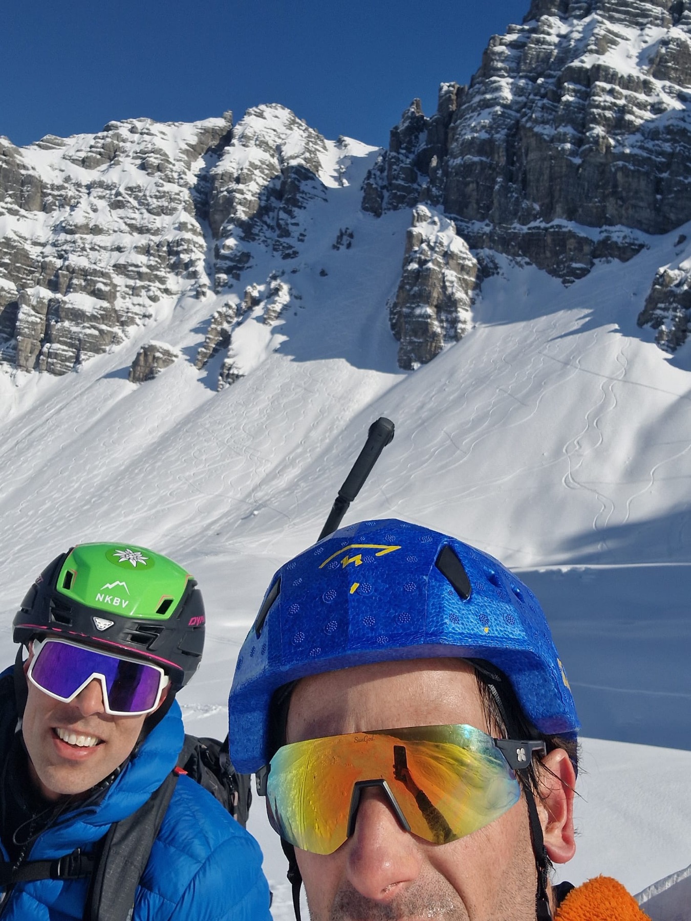 Two of the crew below a steep snowy couloir