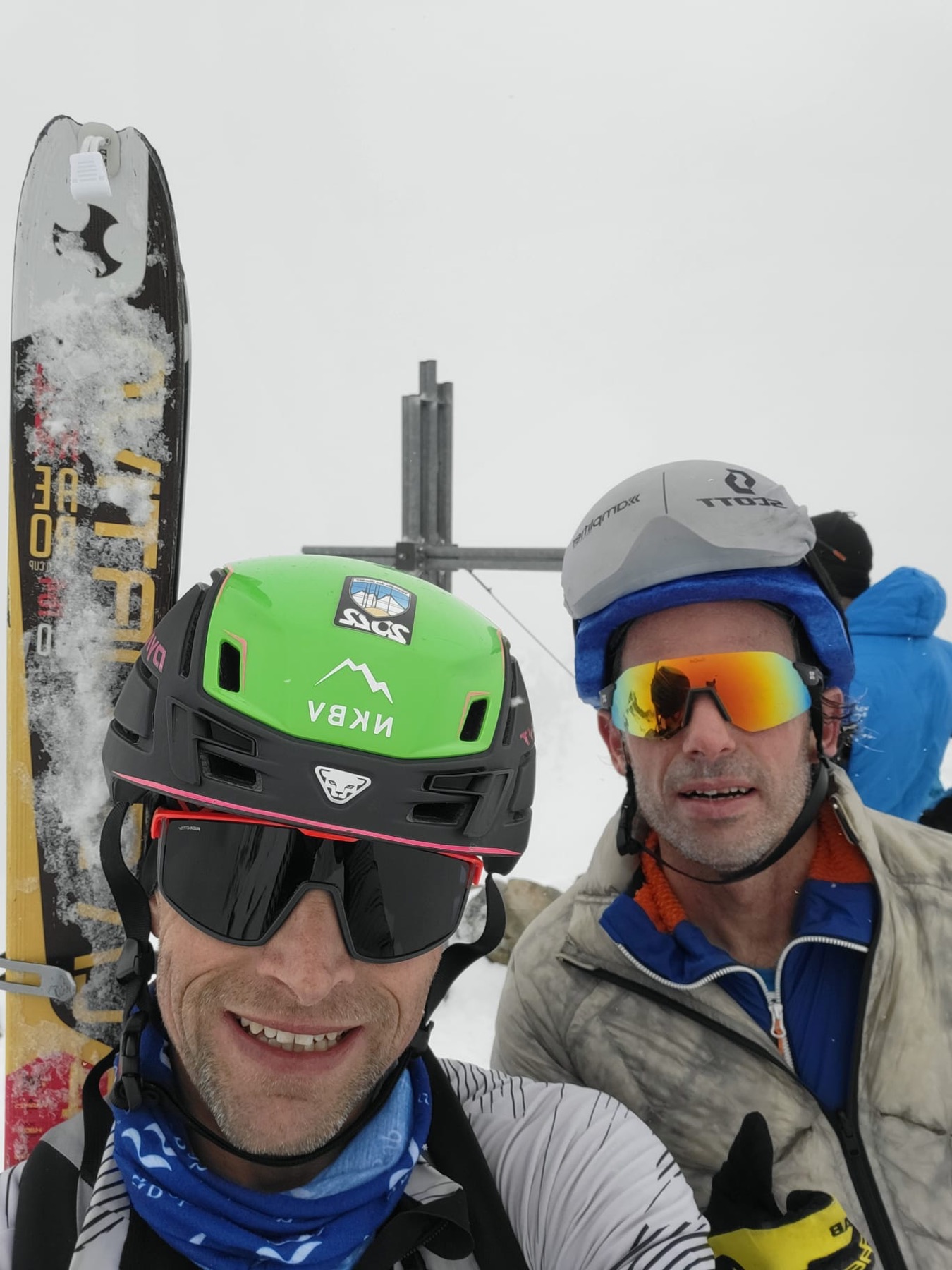 Two of the crew at a summit cross in flat light